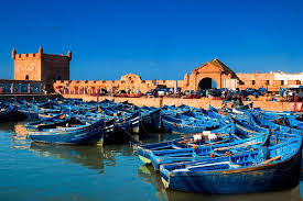 Traditional blue fishing boats in Essaouira harbor with Skala fortress