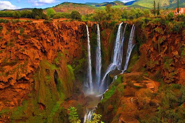 Spectacular Ouzoud Waterfalls cascading down red rocky cliffs covered with green vegetation